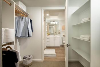 a walk in closet with a door open to a bathroom